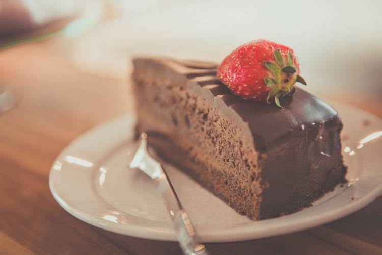 A slice of chocolate cake with a strawberry on top, sitting on a white plate