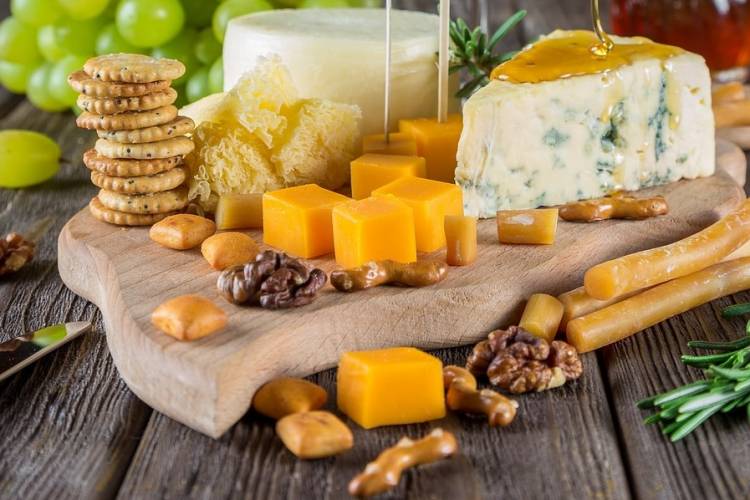  A large assortmemt of cheeses and crackers on a cutting board