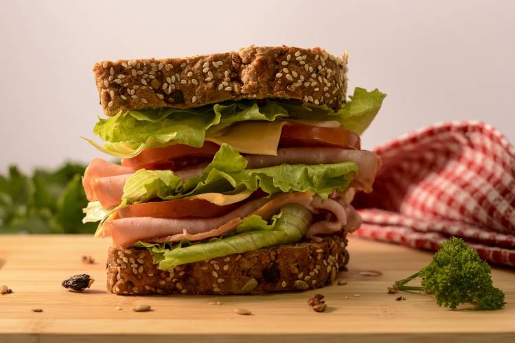 A large ham sandwich sits on a cutting board